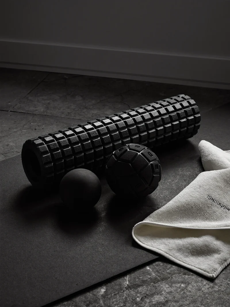Skumrulle og massagebold på mørk måtte ved siden af foldet håndklæde