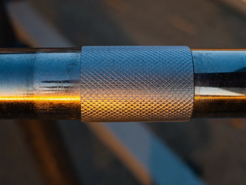 Nærbillede af takket kromhåndtag på håndvægt med synlig metalstruktur